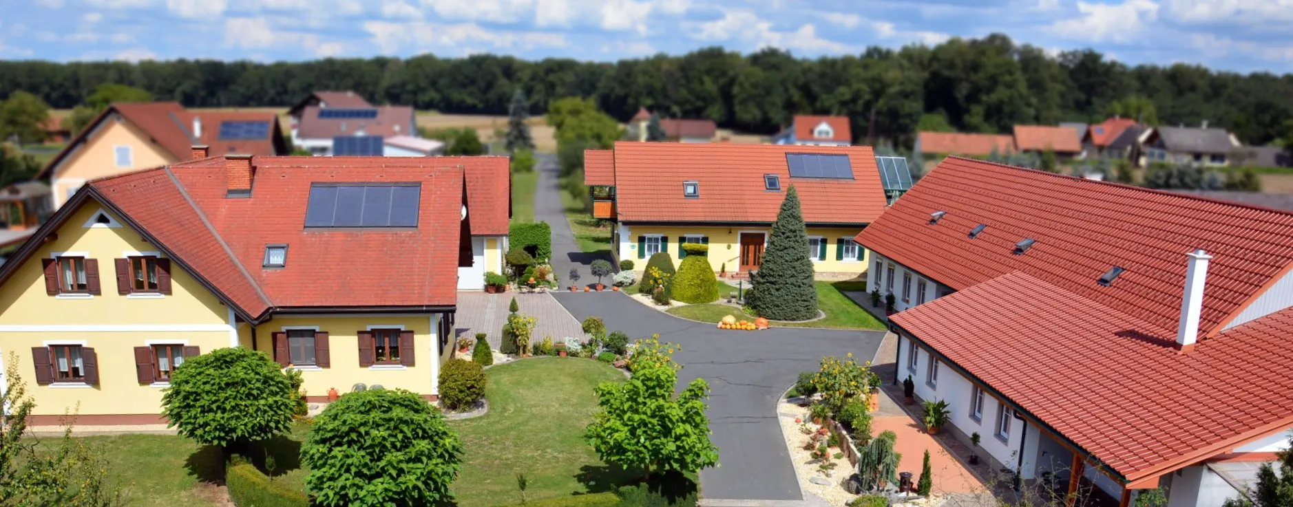 Der Innenhof des Ferienhofs Majczan mit den gelben Ferienhäusern, Garten und Einfahrt